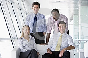 Four businesspeople in office lobby smiling