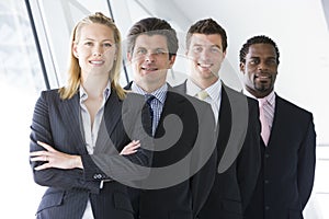 Four businesspeople standing in corridor smiling