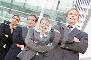 Four businesspeople standing outdoors smiling