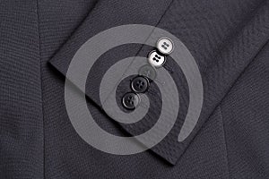 Four buttons on a black business jacket sleeve