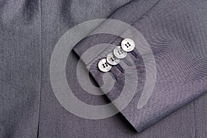 Four buttons on a grey business jacket sleeve