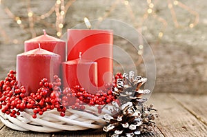 Four candles in a white wreath with red berries on a wooden rustic background with lights. advent calendar for Christmas