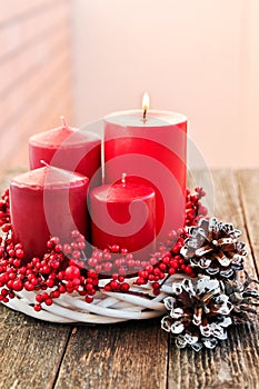 Four candles in a white wreath with red berries on a wooden rustic background with lights. advent calendar for Christmas