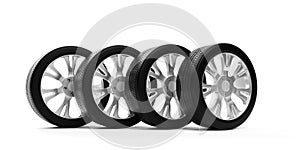 Four car tires with silver rims standing in row on white background