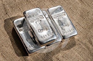 Four cast silver bars against the background of the texture of coarse cloth.