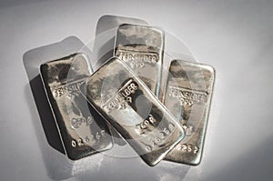Four cast silver bars on a gray background.