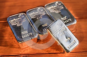 Four cast silver bullion on a mahogany background.