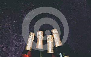 Four champagne bottles on dark background, flat lay