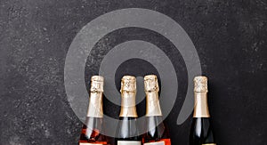 Four champagne bottles on dark background, flat lay