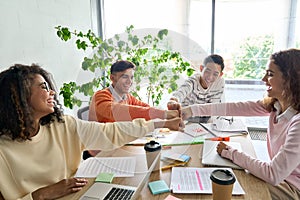 Four cheerful happy startup creative team together in office giving fist bump.