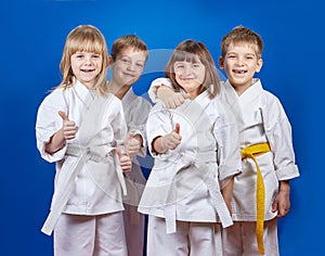 Four cheerful sportsman in karategi are showing finger super photo