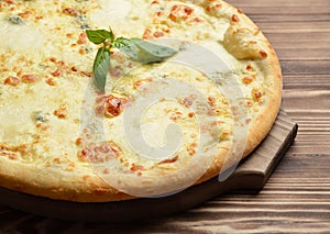 Four cheese pizza quattro fromaggi with basil leaf on a rustic w