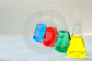 four chemical flasks with a multi-colored liquid are used in the analytical laboratory for research