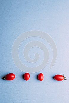 Four cherry tomatoes on a blue background, space for text