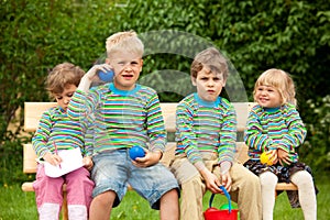 Four chi on bench in park. In identical shirts