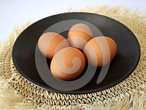 four chicken eggs in a black plate