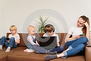 Four children of different ages sitting on couch with phones and laptop. Dependence on social networks