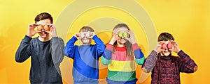 Four children hold Easter eggs to their faces instead of eyes on a yellow background