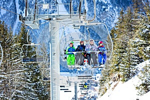 Four children on ski chairlift in the snowy forest