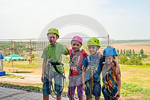 Four children are wearing helmets and climbing clothes and are ready to overcome obstacles in an extreme park.