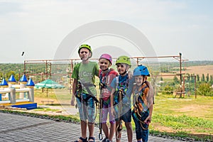 Four children are wearing helmets and climbing clothes and are ready to overcome obstacles in an extreme park.
