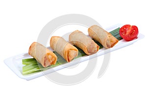 Four Chinese spring rolls on a white long, narrow plate.