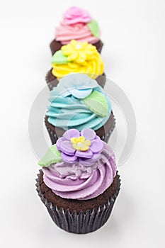 Four Chocolate Cup Cakes With Colorful Icing or Frosting