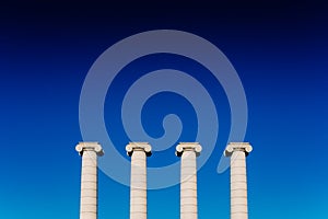 Four classical ionic columns, isolated on blue sky background