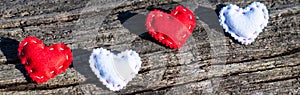 Four cloth hearts, two white and two red ones on a downed tree with shadows