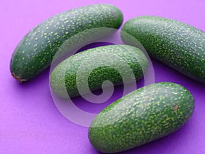 Four cocktail avocados or mini avocados on a purple background