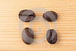 Four coffee beans in differen positions on wooden table