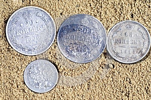 Four coins on sand, old silver coins of Russia of the 18th century