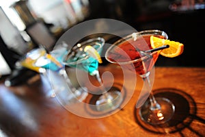 Four colored cocktails on the bar. Yellow, blue, green, red. Decorated with a lemon slice