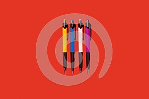 four colored pens lying on a red background