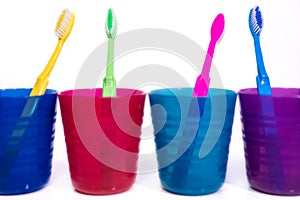 Four colorful cups with toothbrushes, white background