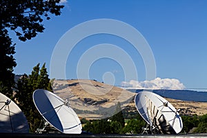 Four Communication Dishes With Hills And Blue Sky Background