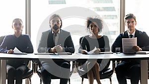 Four confident diverse hr managers sitting at table in row