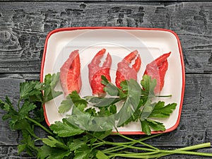 Four crab claws and parsley on a plate on a wooden background