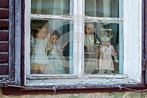 Four creepy dolls dressed in white and with traditional Romanian clothes, displayed in a window, while looking at the people
