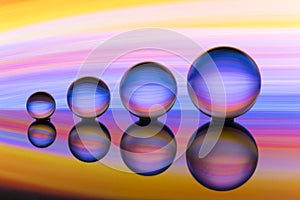 Four crystal balls in a row with colorful streaks of rainbow color behind them