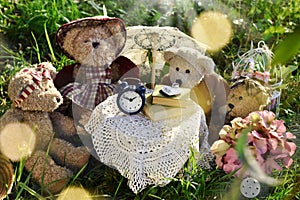 Four cute teddy bear family sitting at the table in the garden