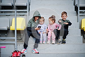 Four cuttie kids sitting on sport area and looking at mobile phone