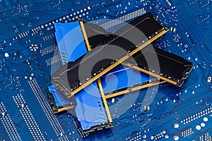 Four DDR memory chips in different colors lying on a blue printed circuit board.