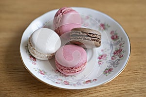 Four delicate macaroons placed on a porcelain plate, confectionery popular for its light texture