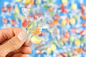 Four different color candies in hand on background of caramels or sweets