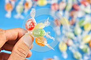 Four different color candies in hand on blue background with caramels or sweets