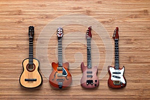Four different electric and acoustic guitars on a wooden background. Toy guitars. Music concept. photo