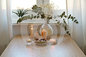 Four different golden burning candles, vase with eucalyptus branches and a bowl with cookies, festive decoration for Advent and