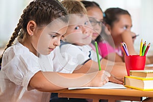 Four diligent pupils studying at classroom