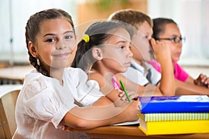 Four diligent pupils studying at classroom